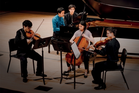 Performers with string instruments and piano on stage